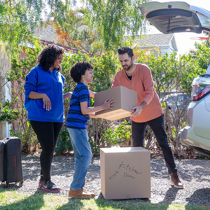 A young family loads boxes into their car have peace of mind provided by the TruStage Auto and Home Program.